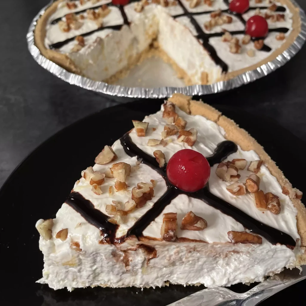 Banana Split Pie topped with whipped cream, cherries, and pecans on a graham cracker crust.